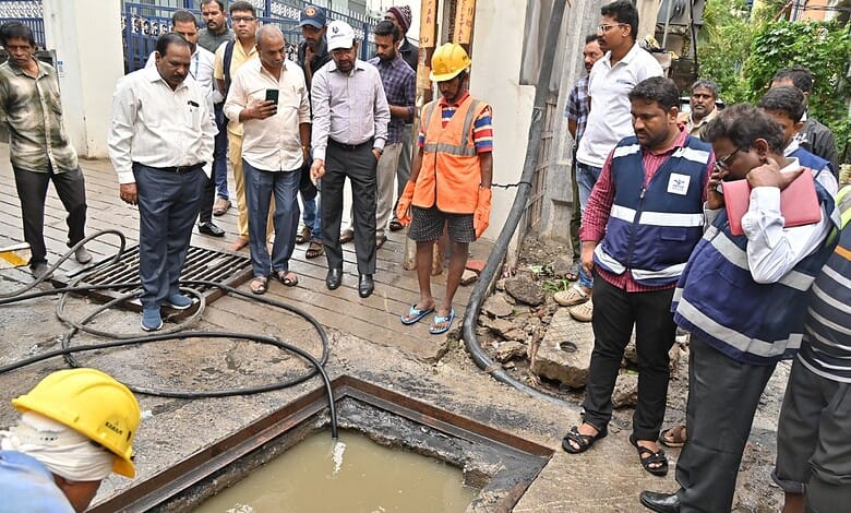 Officials inspect drainage work during Hyderabad rains, flood mitigation efforts in progress.