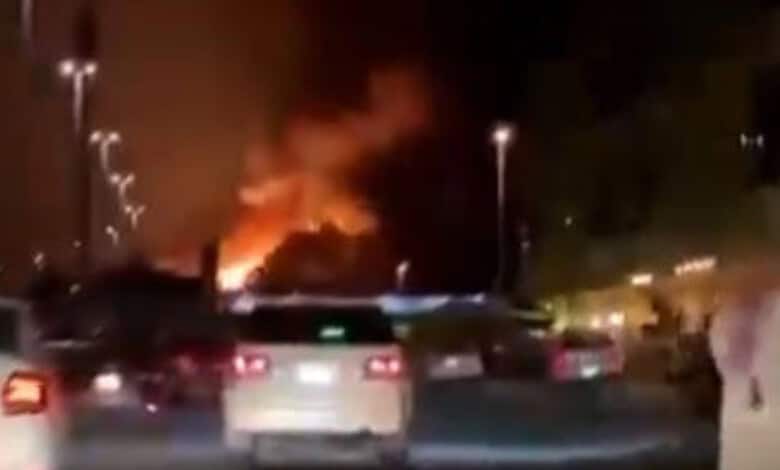 Nighttime scene of a fire at a construction site in Kuwait with smoke and flames visible.