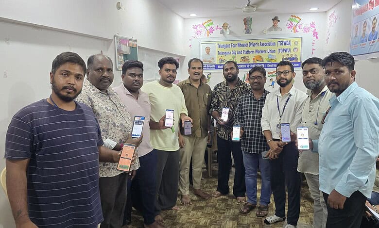 Group of men holding smartphones at a community event in a room with banners.