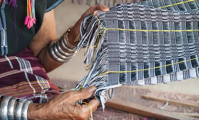 Weaver working on handloom with colourful threads in a traditional setting.
