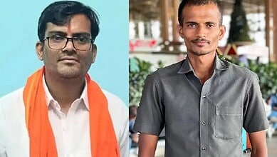 Two men in formal attire, one with glasses and an orange scarf, the other in a grey shirt.