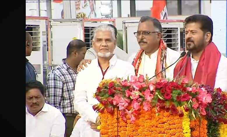 Political leaders at a public event with floral decorations and a large screen in the background.