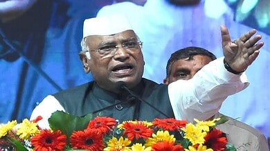 Karnataka politician speaking passionately at a public event with flowers in front.