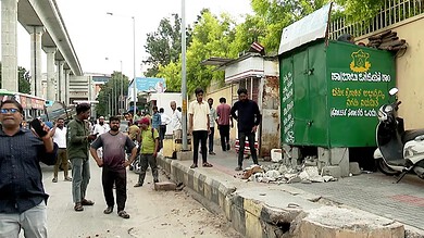 Footpath encroachment removal drive in Bengaluru with people and debris present.