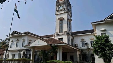 Historic white clock tower building with flag in Mangaluru, India.