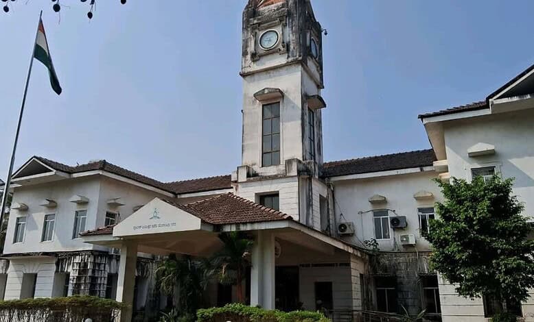Historic white clock tower building with flag in Mangaluru, India.