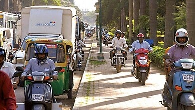 Traffic congestion on a busy Bengaluru street with motorcycles, auto rickshaws, and cars.