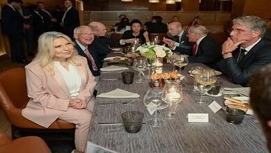 Business meeting with diverse professionals around a table in a formal setting.