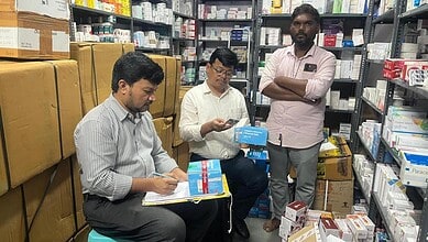 Three men inspecting medical supplies in a pharmacy storage room.