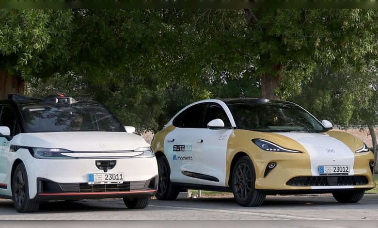 Two self-driving cars displaying Abu Dhabi's new blue autonomous vehicle licence plates.