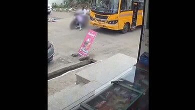 Children near school bus and a woman sitting on the ground in Hyderabad, India.