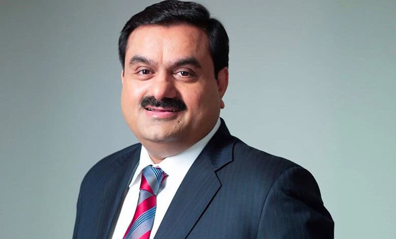 Indian businessman with a mustache in a dark suit and striped tie, smiling at the camera.