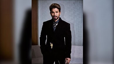 Allu Arjun in a black suit with a gold chain, posing indoors for Hyderabad: Allu arjun's video with fan.