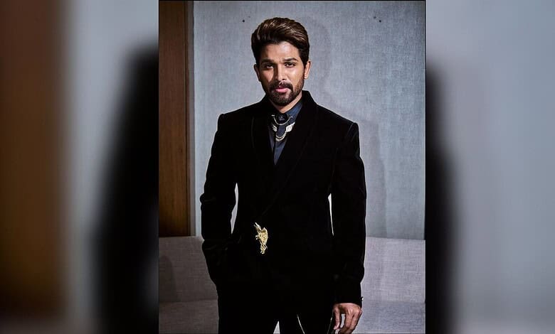 Allu Arjun in a black suit with a gold chain, posing indoors for Hyderabad: Allu arjun's video with fan.