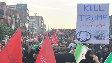 Protesters in Tehran hold signs including one that says 'Kill Trump' during a demonstration.