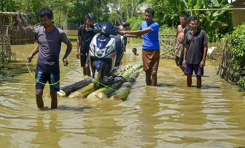 Flood-affected villagers crossing a makeshift bamboo bridge in Assam.