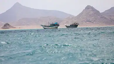Two boats floating in the Red Sea with mountains in the background.