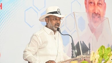 Bandi Sanjay speaking at a public event with a microphone and a transparent shield.