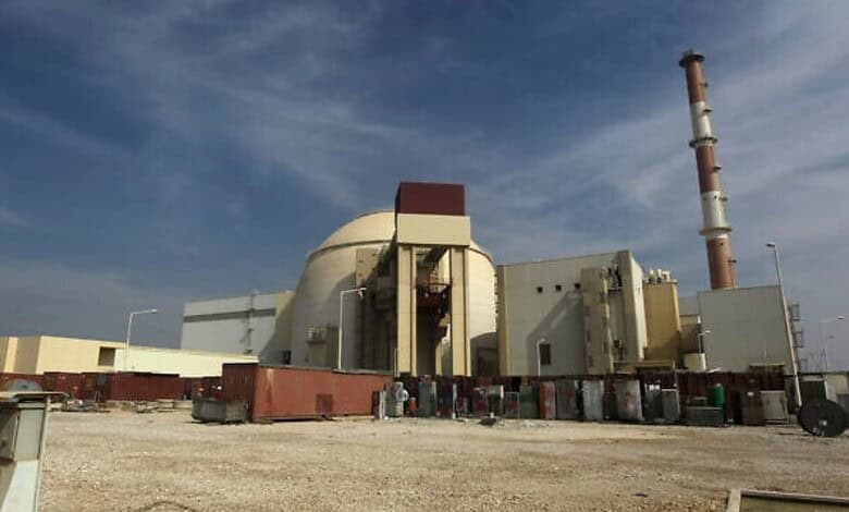 Iran's Bushehr nuclear power plant with cooling tower and reactor building under a blue sky.