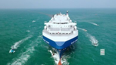 Large cargo ship sailing through the Red Sea near Yemen, with smaller boats around it.