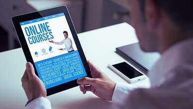 Person holding a tablet displaying online courses related to education and skills development.