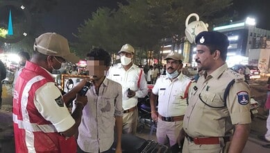 Hyderabad police officers and a man in a crowded street at night, some wearing masks.