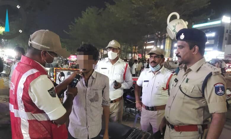 Hyderabad police officers and a man in a crowded street at night, some wearing masks.