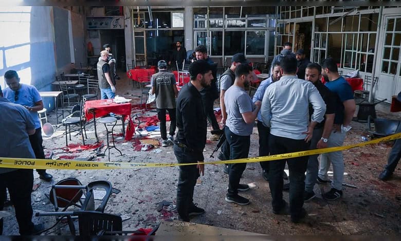 People inspecting damage at a cafe after a bomb blast in Damascus, with debris and police tape present.