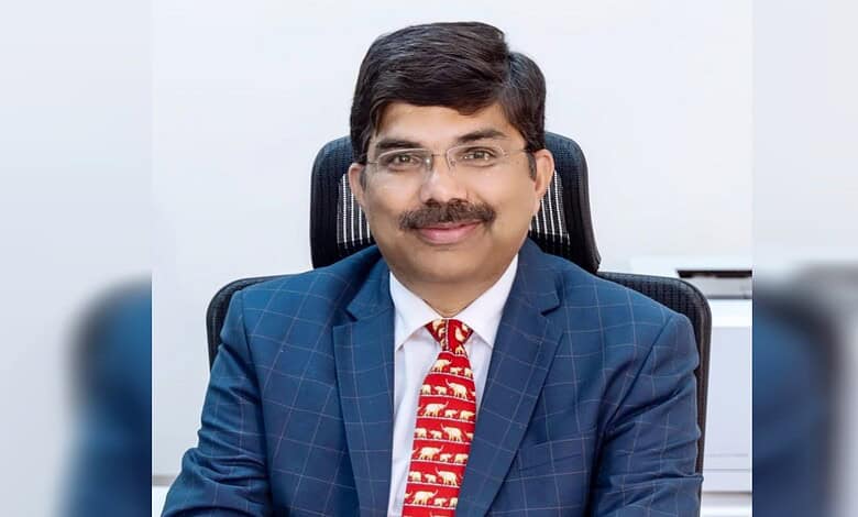 Srikar Reddy, dressed in a blue suit, smiling in an office setting, appointed as India's envoy to Qatar.