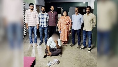 Group of six men and one woman standing with a man kneeling on the floor in front of them.