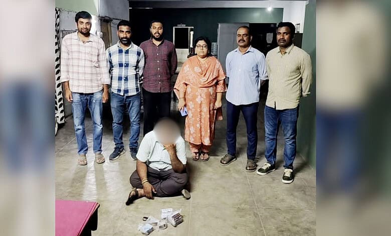 Group of six men and one woman standing with a man kneeling on the floor in front of them.