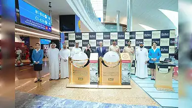 Officials pose beside the Millennium Millionaire draw machines during the Dubai Duty Free draw at Dubai International Airport.
