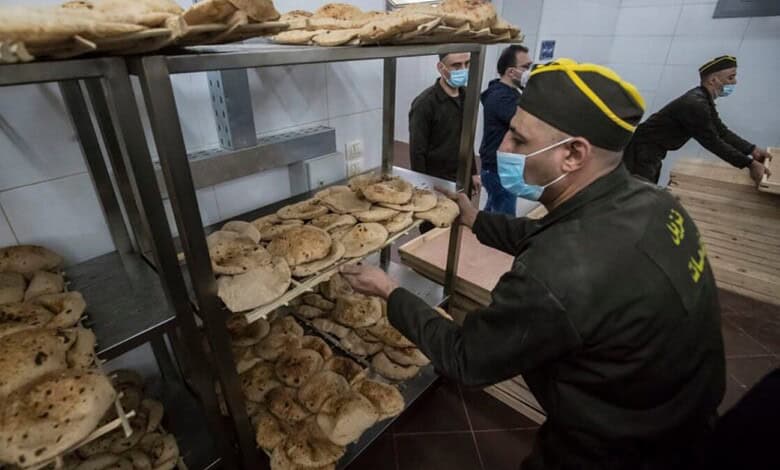 Officials inspecting bread loaves in a bakery, wearing masks and uniforms, in Egypt.