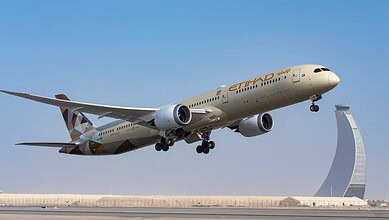 Etihad Airways Boeing 787 aircraft taking off with Dubai skyline in background.