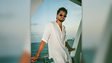 Mr Faisu smiling on a yacht with ocean view in the background, wearing sunglasses and a white shirt.