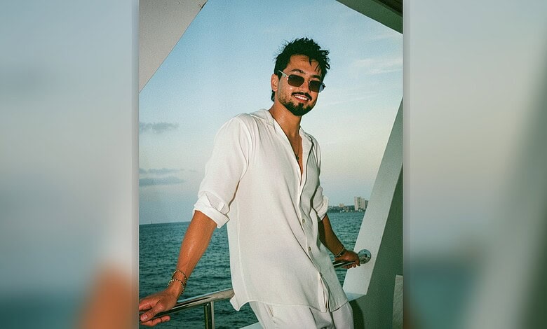 Mr Faisu smiling on a yacht with ocean view in the background, wearing sunglasses and a white shirt.
