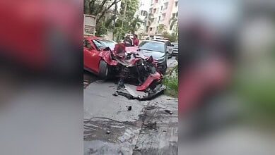 Damaged red Ferrari after crash into apartment in Jubilee Hills, with debris and other vehicles nearby.
