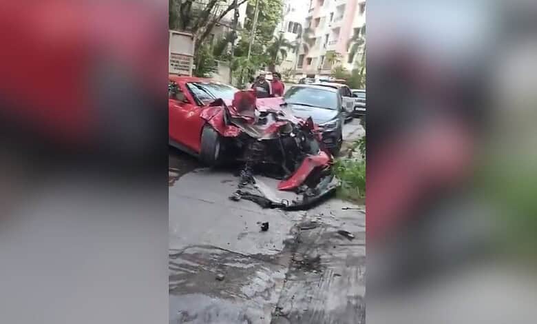 Damaged red Ferrari after crash into apartment in Jubilee Hills, with debris and other vehicles nearby.