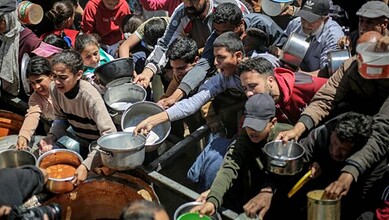 Crowd of people, including children, waiting in line for food distribution in Gaza amid severe food inseu.