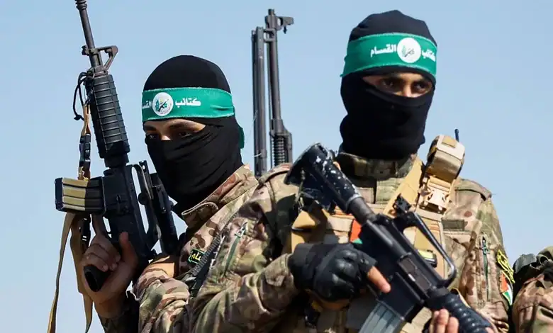 Two armed Palestinian militants in camouflage uniforms and black masks, holding rifles.