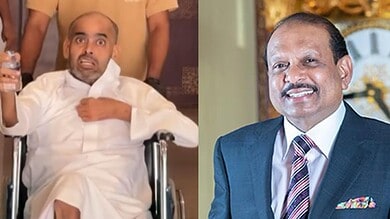 Hyderabadi man in wheelchair with surprised expression, man in suit smiling in background.
