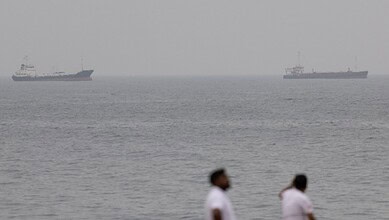 Two merchant vessels anchored in open Gulf waters with the sea stretching to the horizon.