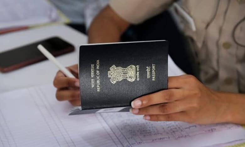 A person holds an Indian passport while completing paperwork at a service desk, representing passport and consular services.