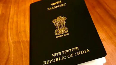 Close-up of Indian passport with emblem and text on cover, on wooden surface.