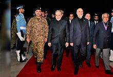 Iran and US officials walking together at a diplomatic event with security personnel in the background.