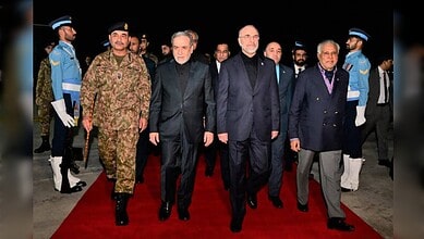 Iran and US officials walking together at a diplomatic event with security personnel in the background.