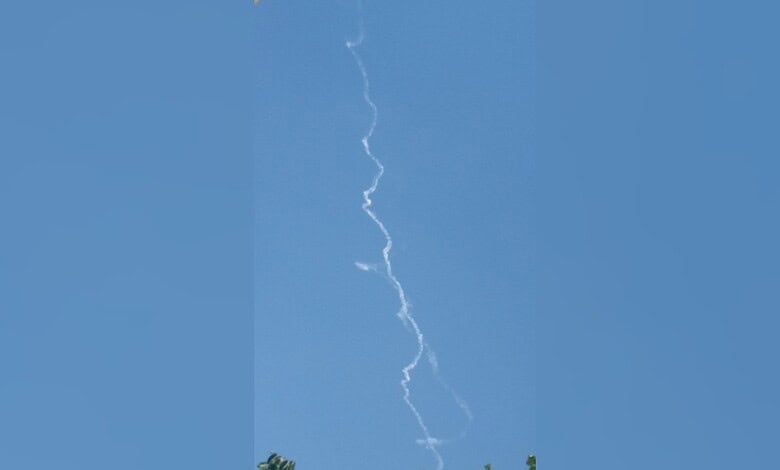A bright lightning bolt streaks across a clear blue sky during daytime.