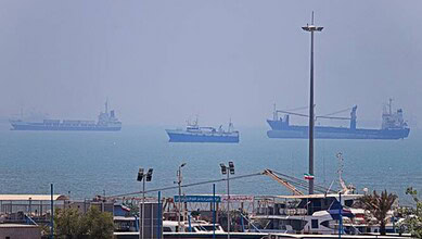 Multiple naval ships anchored in the sea with foggy weather and calm waters.