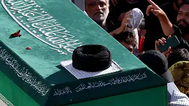 Large crowd gathers around Khamenei's coffin during funeral in Iran, with people paying respects and some.