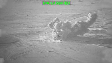 Military aircraft dropping bombs over cloud-covered sky during night.